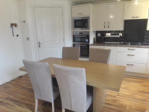 a kitchen with a wooden table and white cabinets at Greenock Home Stay in Wolverhampton