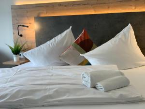 Una cama blanca con almohadas encima. en Residenz Hotel Giessen, en Giessen