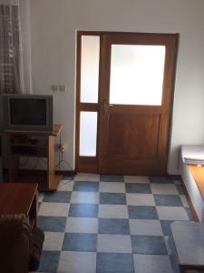 ein Wohnzimmer mit einer Tür und einem TV in der Unterkunft Apartmani Dragica-prizemlje in Kampor