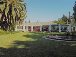una casa con una palmera y una fuente en Happy Lands Farmstay, en Addo