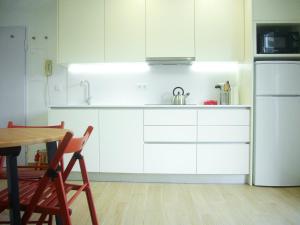 a kitchen with white cabinets and a table and a refrigerator at Castle, Terrace and Relax in Tomar