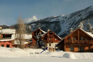 un lodge en la nieve con montañas en el fondo en Le Meï Hameau des Chazals Nevache Hautes Alpes en Névache