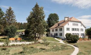 a white house with a garden and trees at Jurabelle in La Côte-aux-Fées