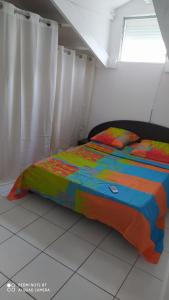 un letto con un piumone colorato in una camera da letto di Appartement marina a Le Gosier