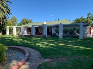 une maison avec un jardin et un étang dans l'établissement Happy Lands Farmstay, à Addo