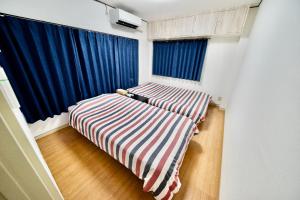1 dormitorio con cama de rayas y cortinas azules en Guest House Re-worth Sengencho1, en Nagoya