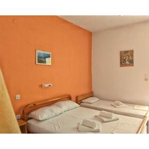 two beds in a room with orange walls at Artolithia Apartments in Riza