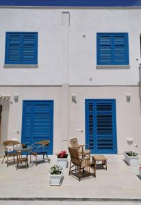 a group of chairs and blue doors on a building at Cuore di Conchiglia in Custonaci