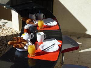 une table avec des assiettes de nourriture et des tasses de jus d'orange dans l'établissement Hôtel Villa Boeri, à Beausoleil