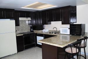 a kitchen with black cabinets and a white refrigerator at Rosarito Inn in Rosarito