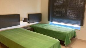 2 camas verdes en una habitación con ventana en Franciscos em Cabanas Golf en Conceição