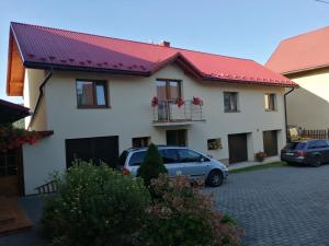 a house with a red roof and cars parked in a driveway at Pokoje u Jarka in Krzyżowa
