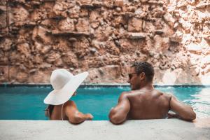 um homem e uma mulher sentados ao lado da água em Ahava Hotel em Playa del Carmen
