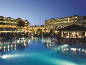 a hotel with a large swimming pool at night at Lindos Princess Beach Hotel in Lartos