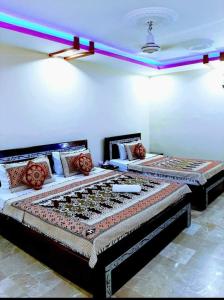 dwa łóżka siedzące w pokoju z oświetleniem w obiekcie Gulshan Palace Near Millennium Mall w mieście Karaczi