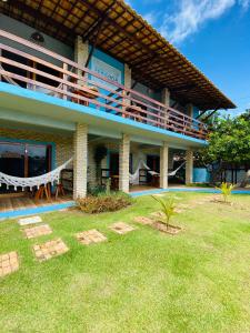 a house with a balcony and a grass yard at Pousada Manga Azul in Barra de Camaratuba