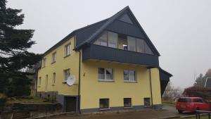una casa amarilla y negra con techo negro en Ferienwohnung Ilse, en Crottendorf