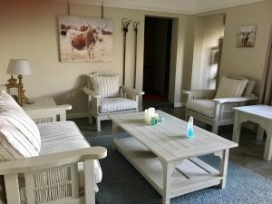a living room with white furniture and a table and chairs at Kingfisher Cottage in Umkomaas