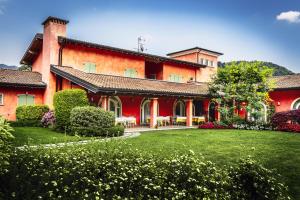 a large red building with a lawn in front of it at Hotel Al Poggio Verde in Barghe