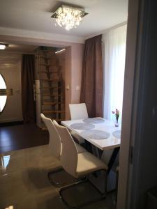 a dining room table with white chairs and a chandelier at Kupola Apartman in Szeged