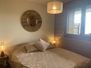 土绪尔ODYSSEE D103 Appartement chaleureux sur les pistes的一间卧室配有一张带镜子和灯的床