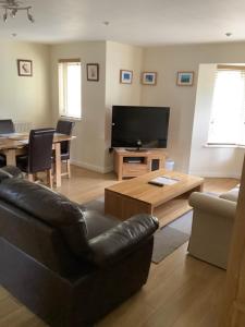 a living room with a black leather couch and a television at Simpson's Apartments Rugby Ltd in Rugby