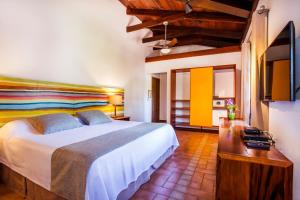 a bedroom with a large bed and a wooden table at Hotel Aldeia de Sahy in Barra do Sahy