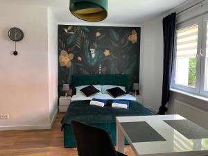 a bedroom with a green bed with a floral wall at Apartament MATEO in Malbork