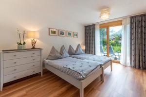 a bedroom with a bed and a dresser and a window at Haus Alpine in Zermatt