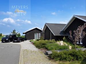 a house with cars parked in front of it at Schwarzes Holzferienhaus mit Sauna -- L I E B L I N G S P L A T Z -- an der Ostsee, Zierow bei Wismar, Strand 500m, alles inklusive in Zierow