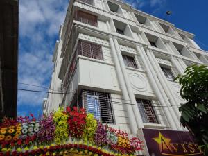 a white building with flowers in front of it at Hotel Avisha in Kolkata