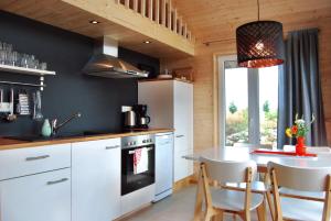 a kitchen with white cabinets and a table with chairs at Schwarzes Holzferienhaus mit Sauna -- L I E B L I N G S P L A T Z -- an der Ostsee, Zierow bei Wismar, Strand 500m, alles inklusive in Zierow