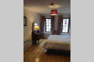 a bedroom with a bed and a desk and two windows at Apartment 4, Clifden Bay Apartments in Clifden +6 photos
