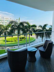 a balcony with chairs and a view of palm trees at Area Ocean De luxe sanitizado in Nuevo Vallarta