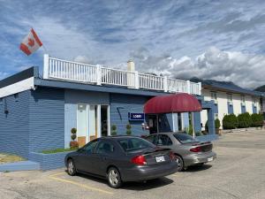 two cars parked in front of a blue building at Valemount Vacation Inn in Valemount