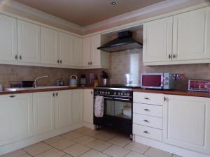 a kitchen with white cabinets and a black stove top oven at Dunmor House - Charming Victorian Period Property in Callander