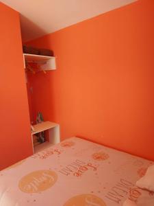 ペズナにあるLes Gîtes De Yayouのオレンジ色の壁のベッドルーム1室、ベッド1台が備わります。