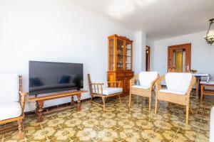 a living room with a flat screen tv and chairs at Skyline Cala Nau in Cala Millor