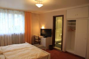 um quarto com uma cama e uma televisão de ecrã plano em Hotel Die Post em Offenbach
