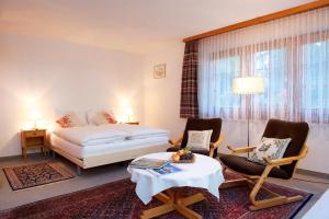 ein Hotelzimmer mit einem Bett, 2 Stühlen und einem Tisch in der Unterkunft Haus Tuscolo in Zermatt
