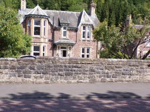 a large brick house with a stone wall at Dunmor House - Charming Victorian Period Property in Callander