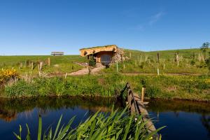 a river with a bridge in the middle of a field at Shepherd's Loch Glamping in Turriff