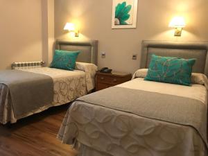 two beds in a hotel room with green pillows at Hotel Crillon Mendoza in Mendoza