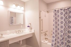 a bathroom with a sink, toilet, mirror and shower curtain at Linekin Bay Resort in Boothbay Harbor