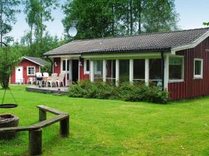 a red house with a porch and a yard at 6 person holiday home in HÅCKSVIK-By Traum in Håcksvik