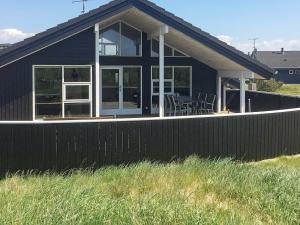 a black house with a fence in front of it at 6 person holiday home in Ringk bing in Søndervig