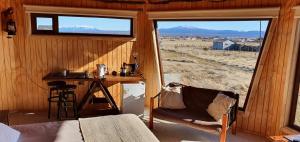 um quarto com uma cama e uma secretária com uma janela em Cabañas y Casa Kauken em Puerto Natales
