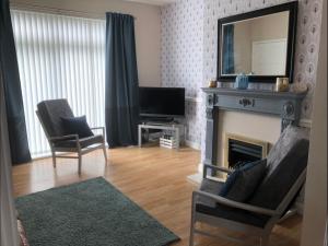 a living room with a fireplace and a television at Bea's Cottage in Newbiggin-by-the-Sea