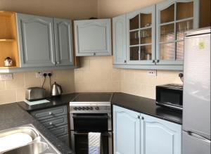 a kitchen with white cabinets and a stove top oven at Bea's Cottage in Newbiggin-by-the-Sea