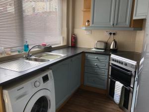 a kitchen with a washing machine and a sink at Bea's Cottage in Newbiggin-by-the-Sea